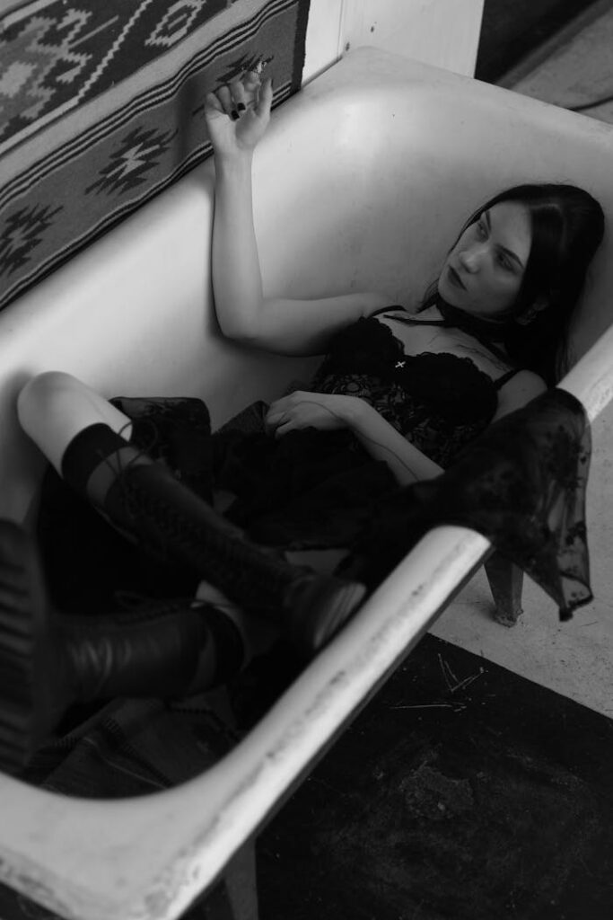 Artistic black and white portrait of a woman lying in a bathtub, conveying introspection.